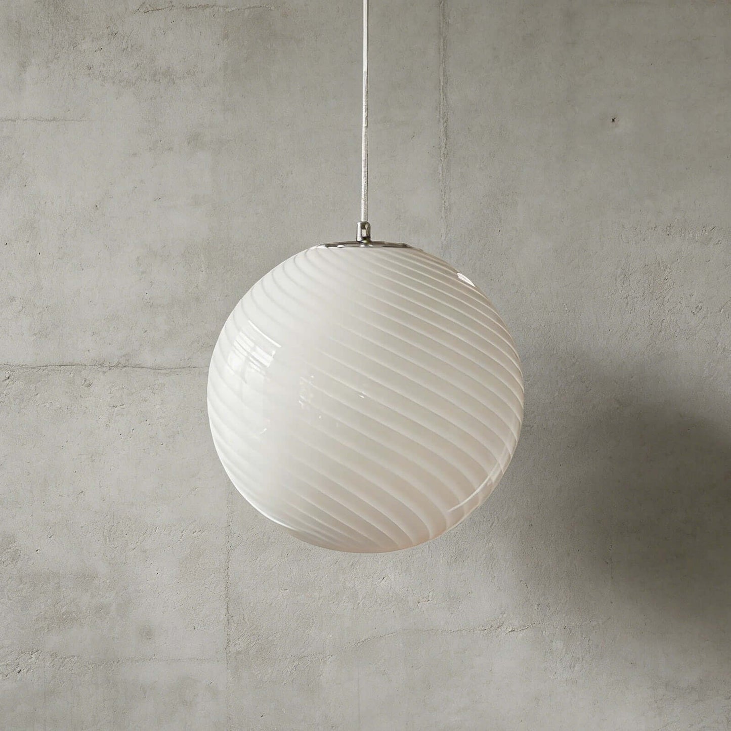 A modern spherical pendant light with a white glass shade featuring a subtle swirling pattern, suspended against a textured grey concrete wall background.