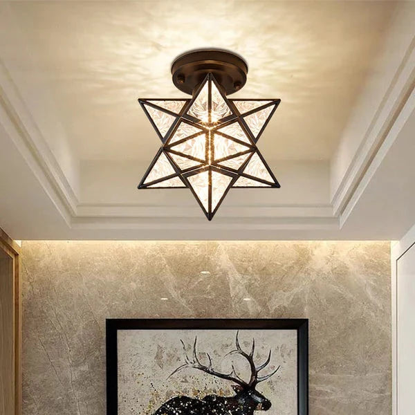 Modern black five-pointed star flush mount ceiling light with textured glass panels emitting a warm glow, installed in a contemporary interior space.