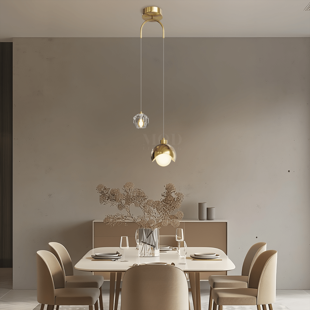 Gold dual-drop pendant with crystal accent above a dining table