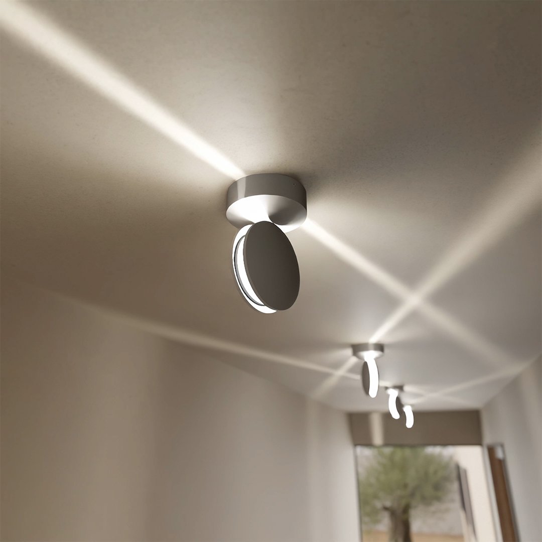 White rotating-disc ceiling spotlight directing light across a ceiling