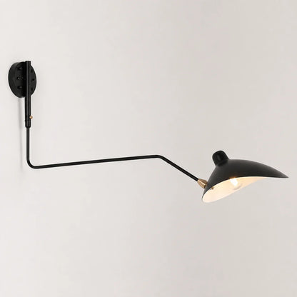 An adjustable black swing-arm wall lamp with a curved metal shade, mounted on a plain white wall and illuminated to cast a warm, inviting glow.