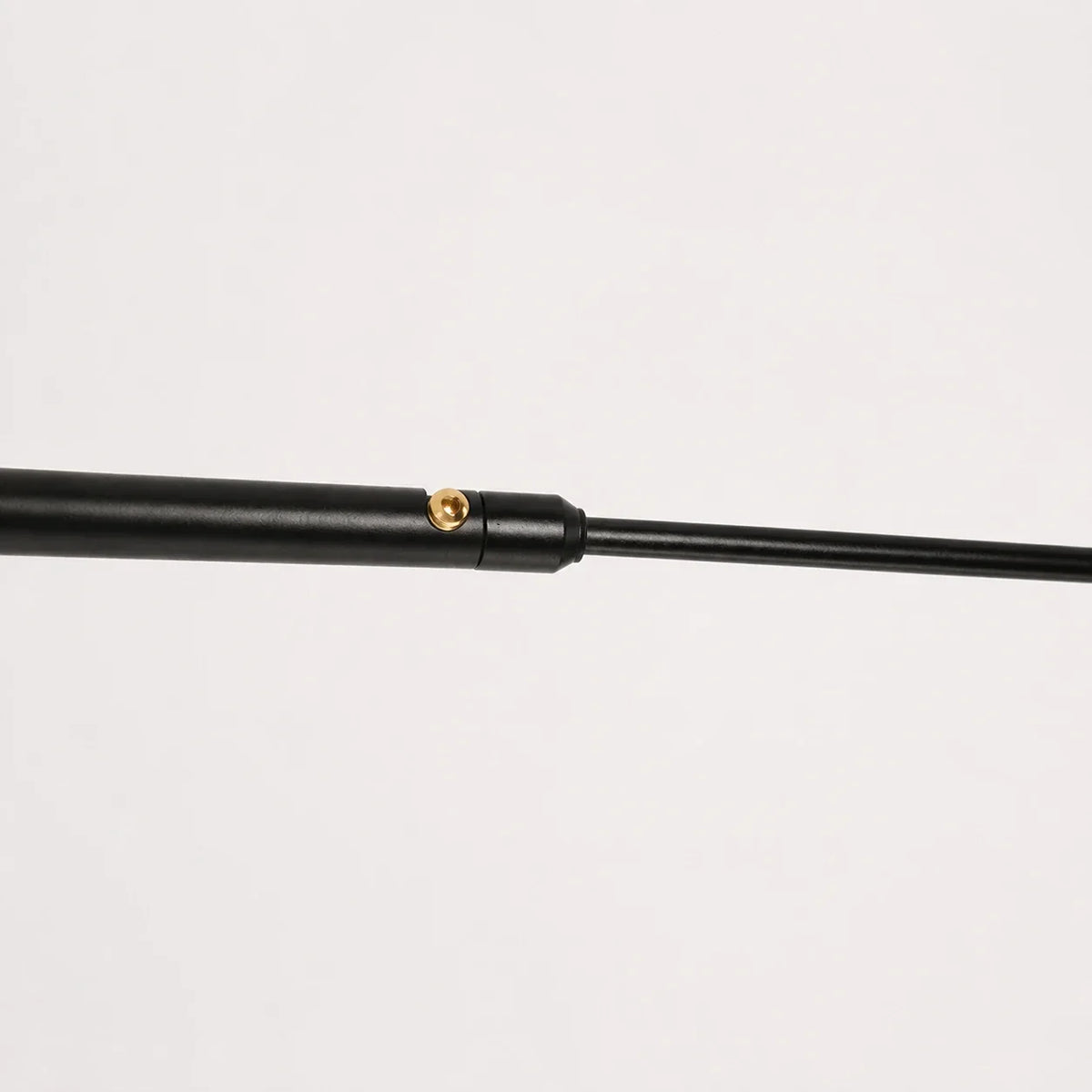 Close-up of the adjustable black metal swing arm of the wall lamp, showing the brass adjustment screw mechanism against a white background.