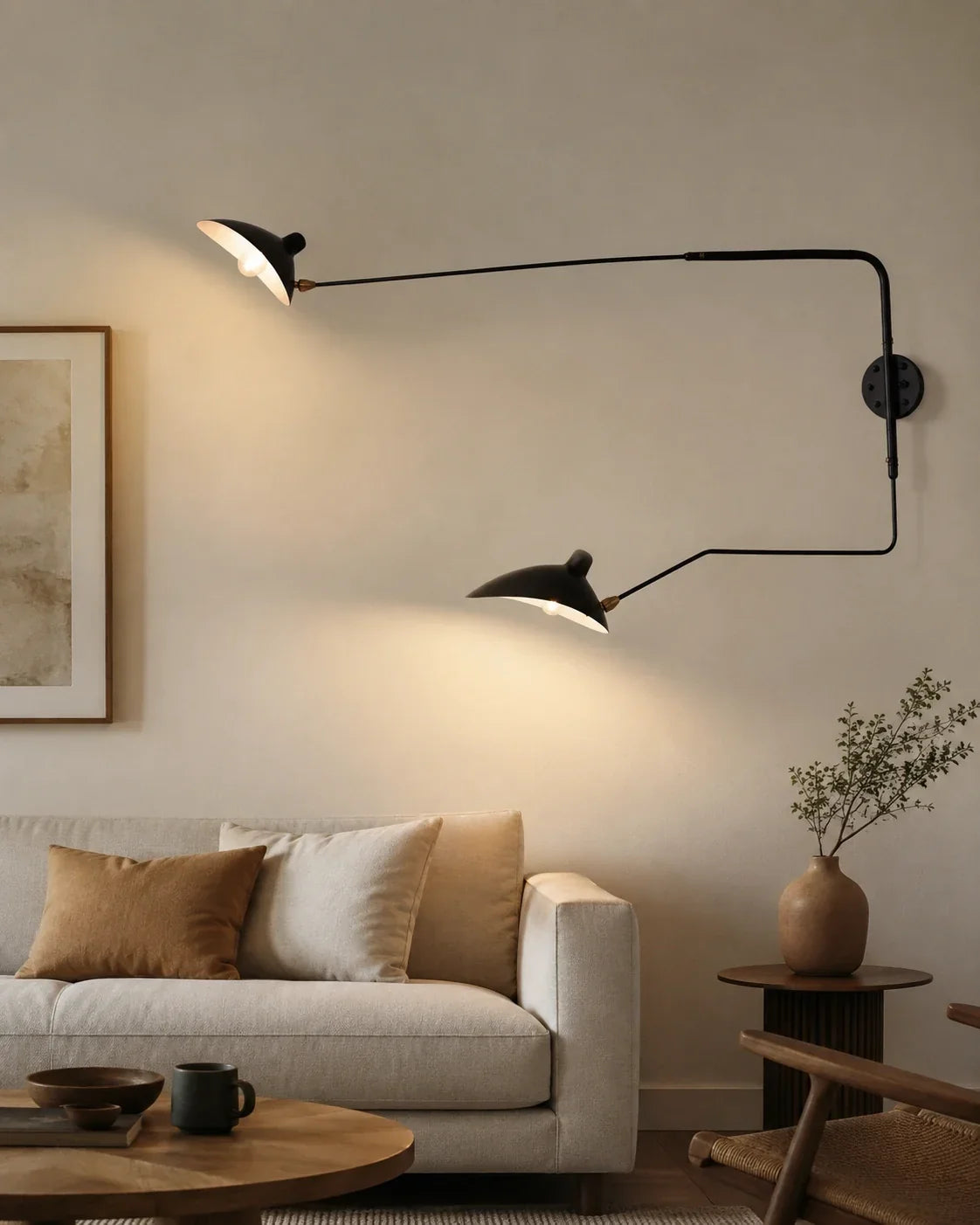 A black adjustable swing-arm wall lamp with two illuminated lights mounted on a neutral wall above a modern sofa in a cosy living room.