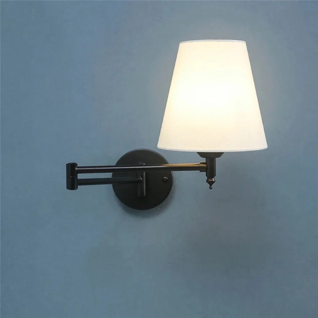 Modern adjustable swing arm wall lamp featuring a black metal arm and a glowing white fabric tapered shade, mounted on a textured blue wall.