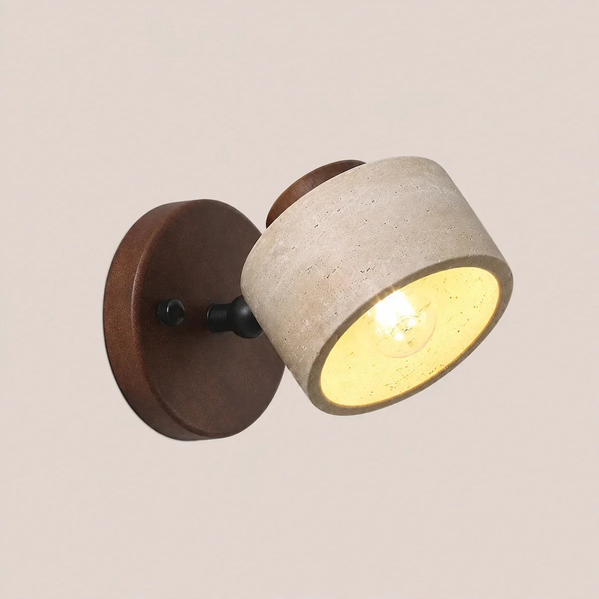 An adjustable wall light with a cylindrical travertine stone shade and a dark walnut wood base, illuminated to show a warm, glowing light.