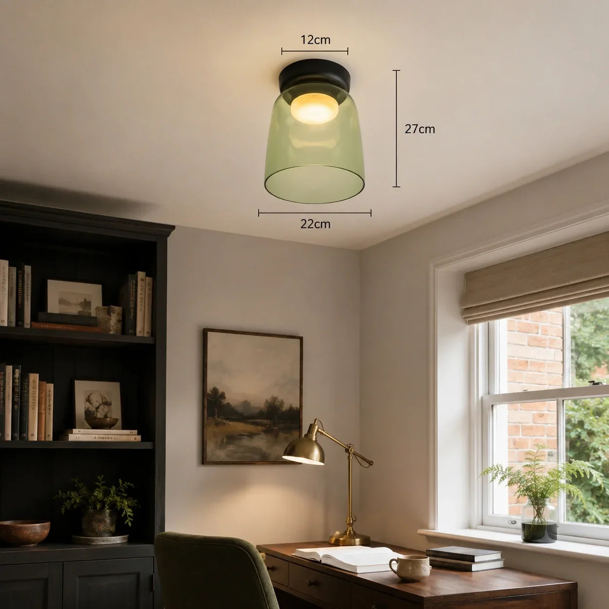 An Art Deco green glass ceiling light with dimensions, emitting a warm glow in a cosy home office study above a wooden desk and chair.