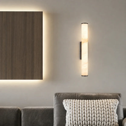Art Deco LED wall light with a glowing simulated marble shade, mounted on a neutral wall above a grey sofa with a textured knitted cushion.