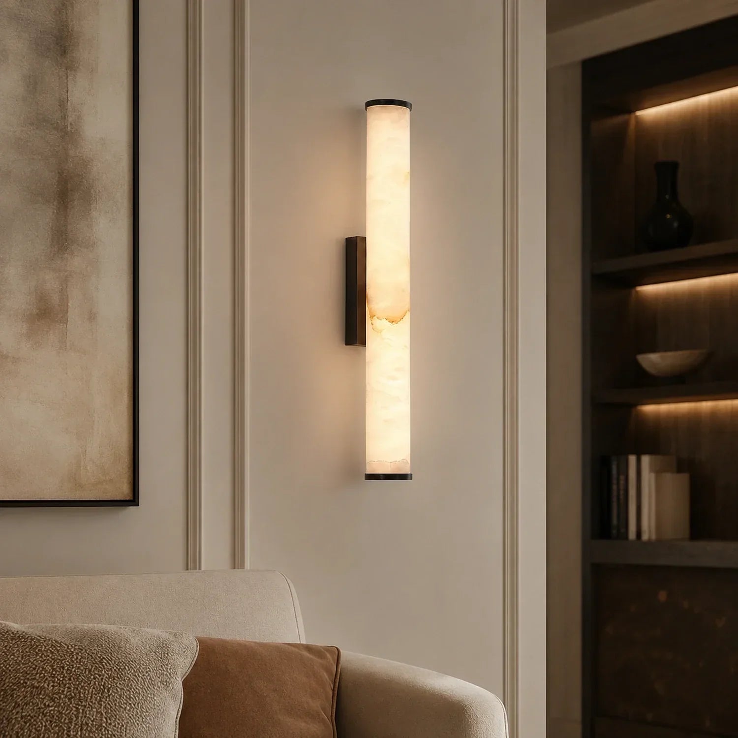 Art Deco LED wall light with a glowing, cylindrical simulated marble shade, mounted vertically on a neutral wall in a modern living room.