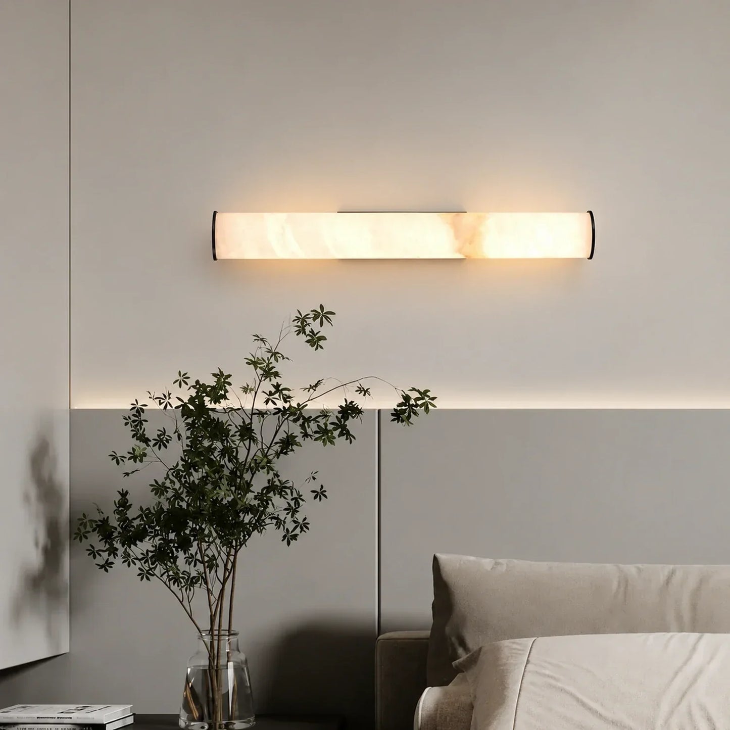 An elegant horizontal Art Deco LED wall light with a simulated marble shade, emitting a warm glow above a bed in a modern bedroom.