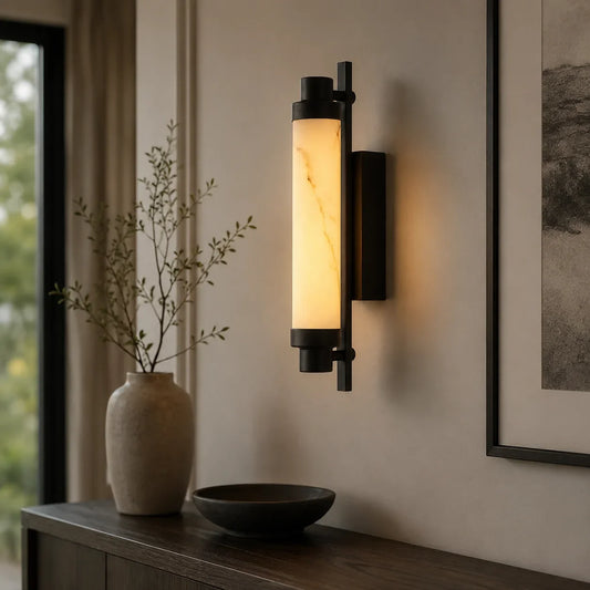 Art Deco LED wall light with a black metal frame and a glowing warm white marble-effect cylindrical shade, mounted on a neutral interior wall.