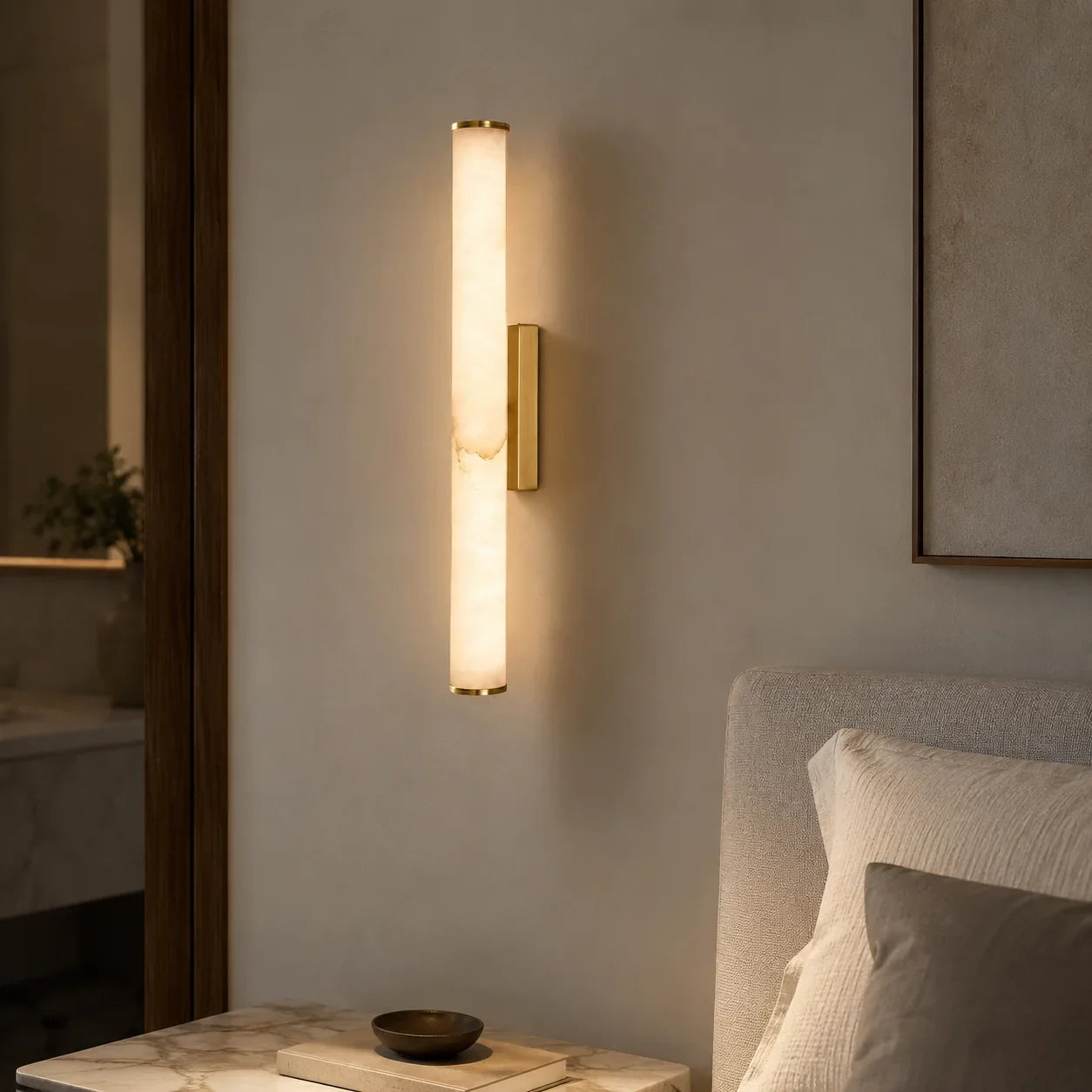 Gold Art Deco LED wall light with a glowing warm white simulated marble shade, mounted on a neutral bedroom wall next to a bed.