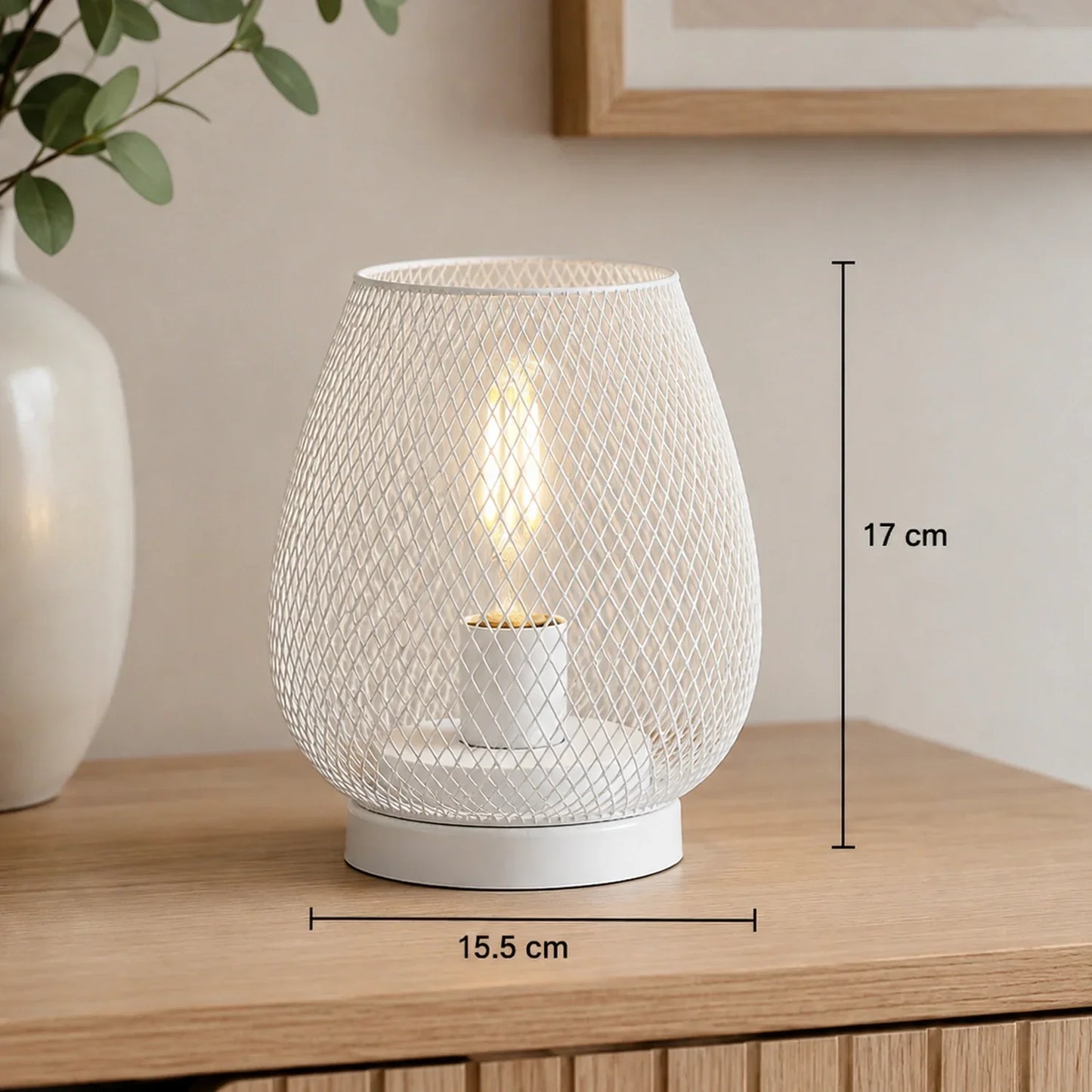 White battery-operated LED table lamp with a decorative mesh design, measuring 17 cm in height and 15.5 cm in width, displayed on a wooden surface.