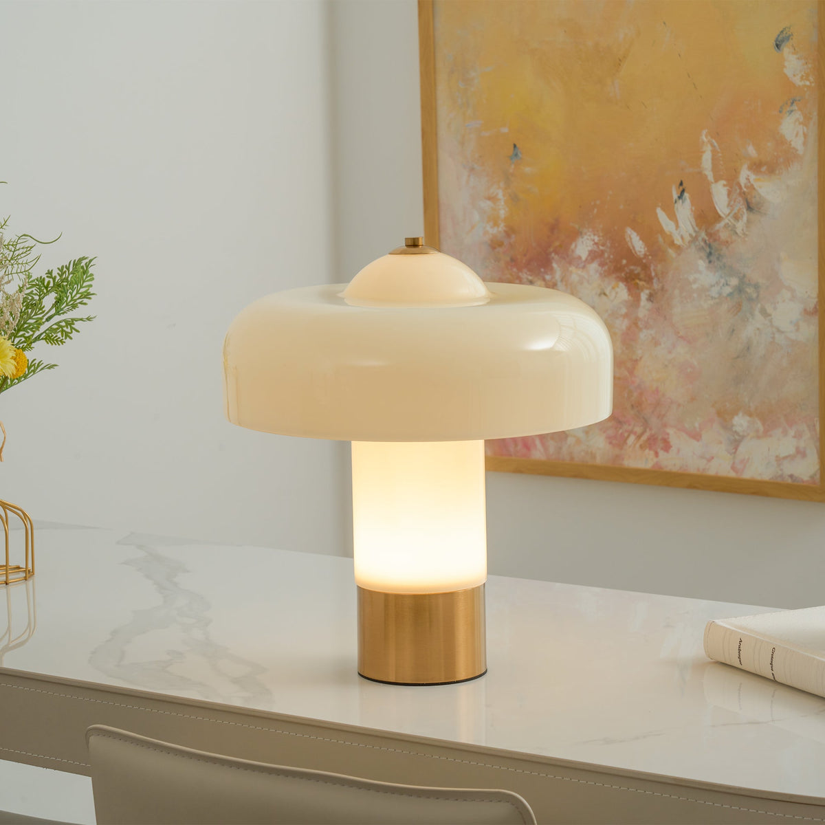 Illuminated glass table lamp near wall artwork