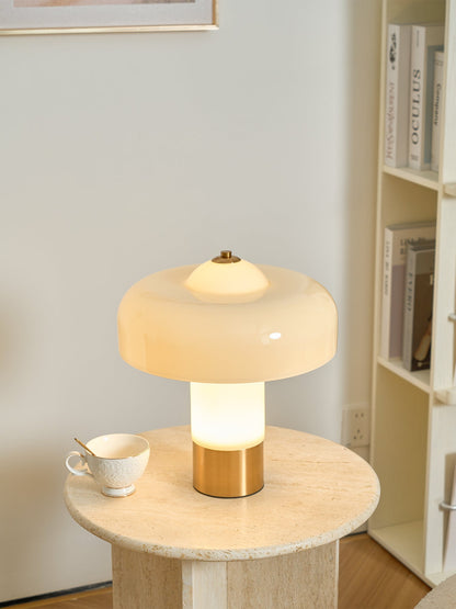 Glowing beige glass lamp beside a cup
