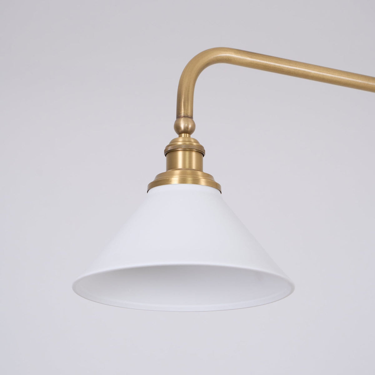 Close-up of ceramic pendant shade and curved brass arm