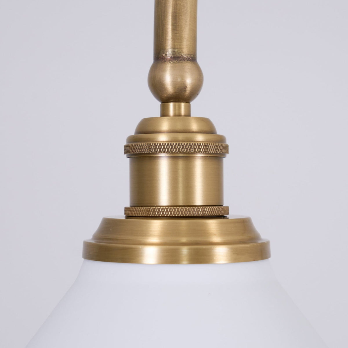 Brass fitting above a white ceramic pendant shade