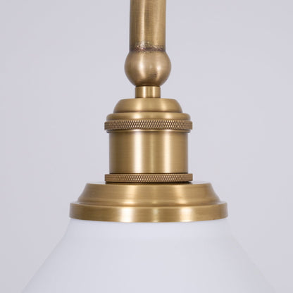 Brass fitting above a white ceramic pendant shade