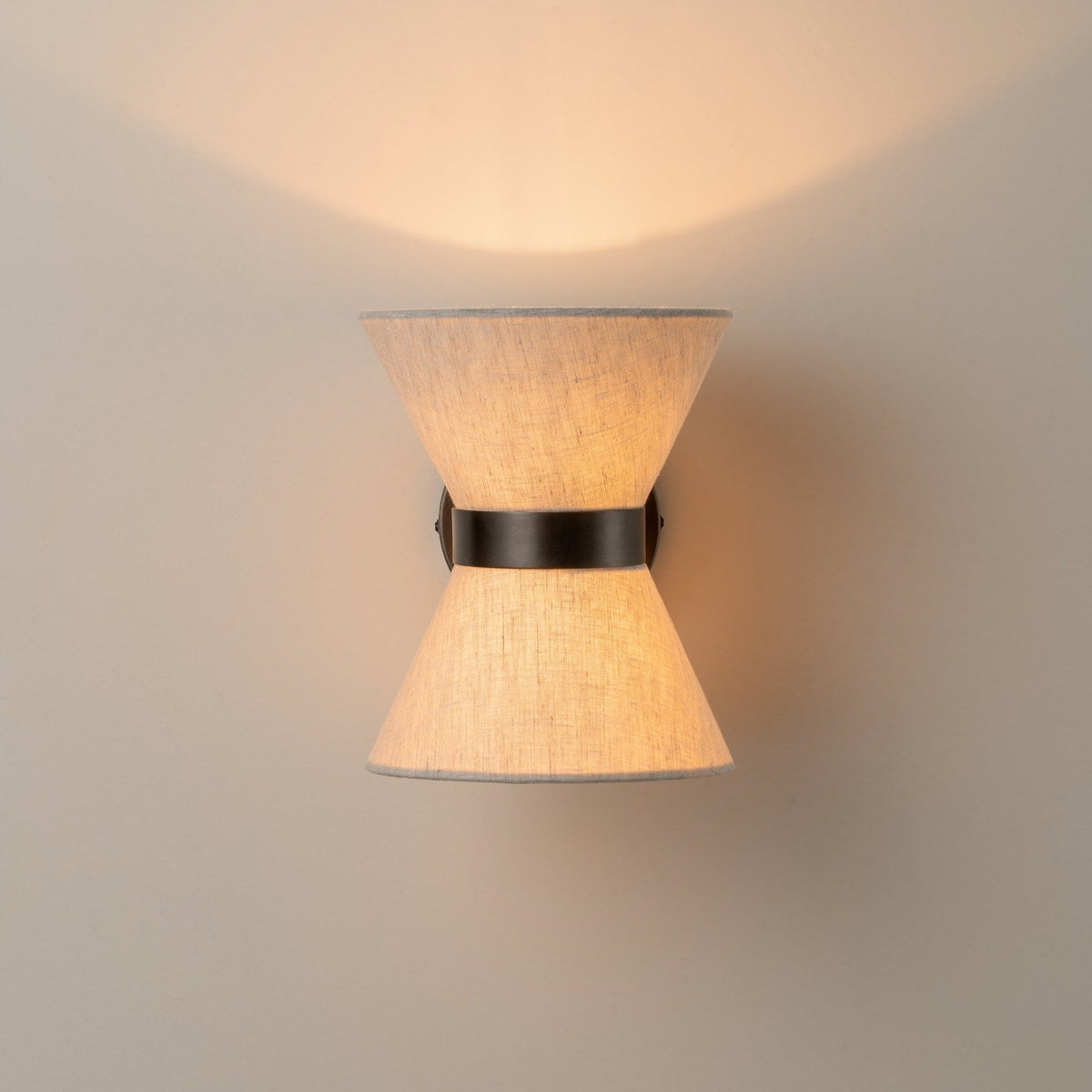 Bronze and linen wall light casting warm light above and below