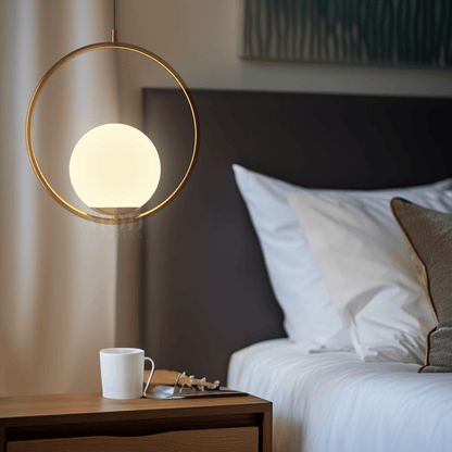 Brushed gold circular cage pendant light beside a bed
