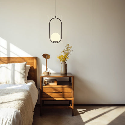 Black oval cage pendant light above a bedside table