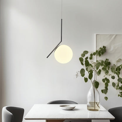 Black angled-frame pendant light with glass globe above a dining table
