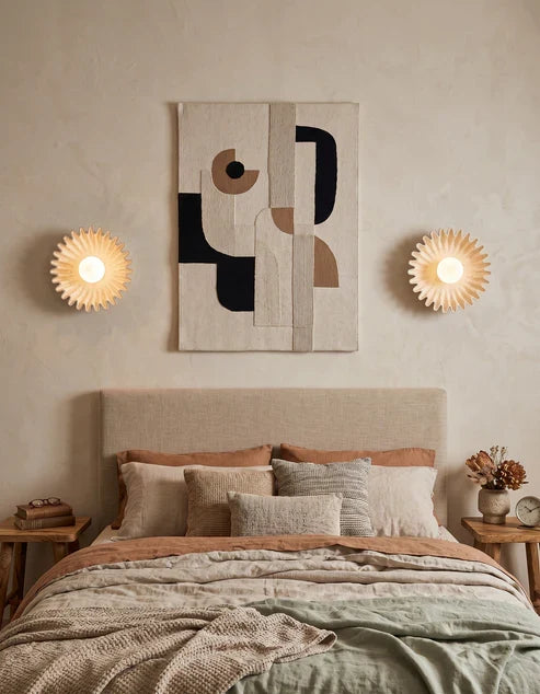 Beige ceramic flower sconces beside a bed