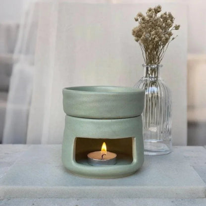 Mint ceramic oil burner beside a vase