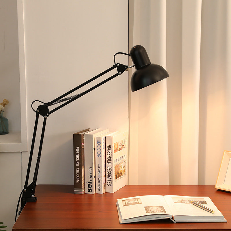 Black clamp desk lamp beside an open book