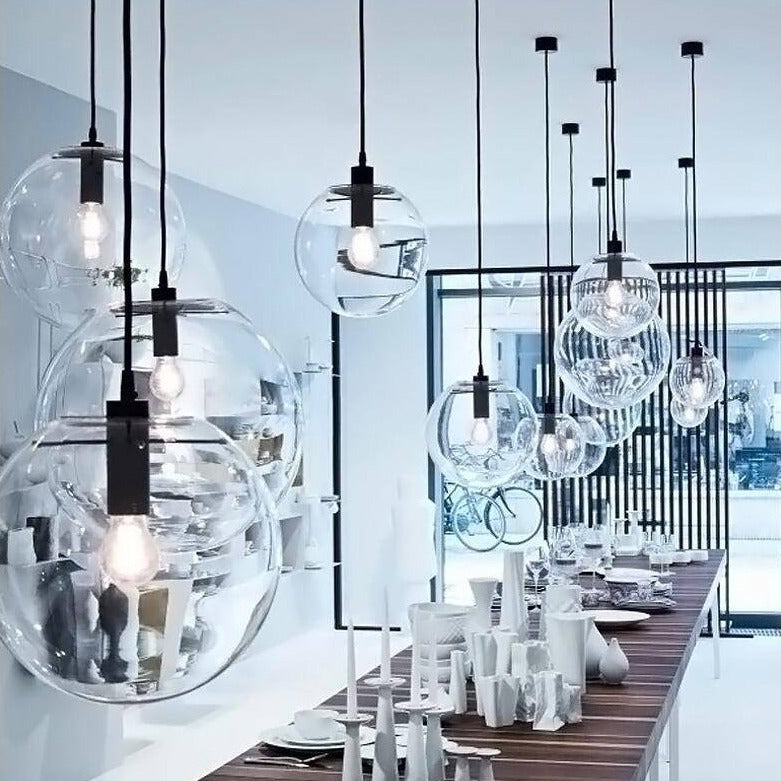 Clear glass globe pendants with black fittings above a table