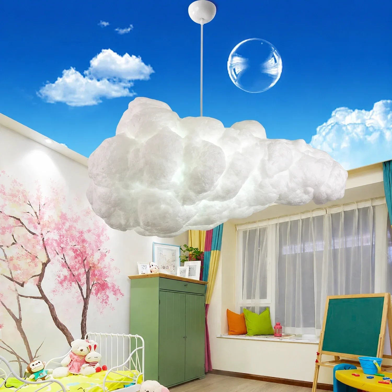 Sculptural cloud pendant light hanging in a colourful children's bedroom with a painted tree mural, green cabinet, and a bright blue sky ceiling.
