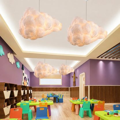 Four fluffy cloud pendant lights hanging from the ceiling in a colourful nursery or playroom with children's tables and chairs and purple walls.