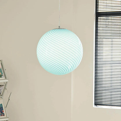 A modern spherical pendant light with a pale blue and white swirl glass design, suspended from a simple chrome fitting in a bright, neutral room.