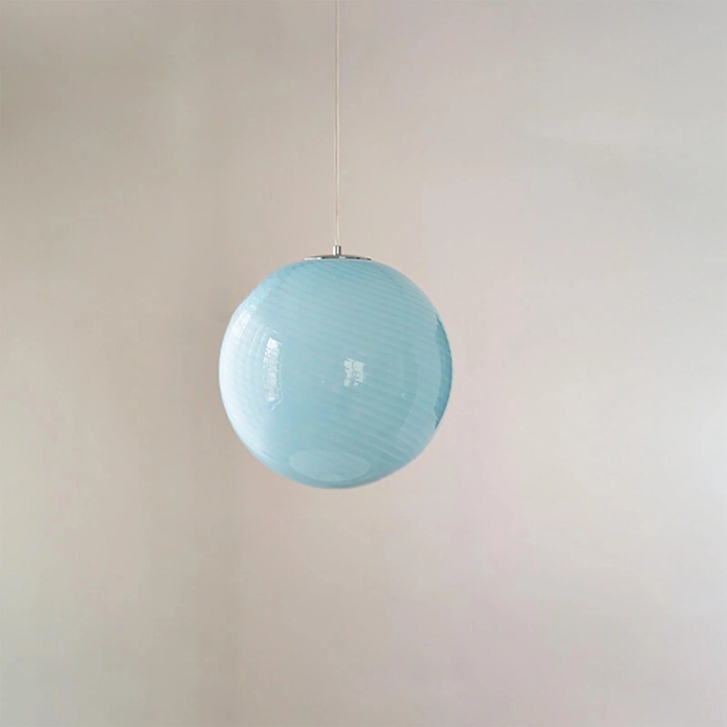 A modern spherical pendant light featuring a pale blue glass shade with a subtle white swirl pattern, suspended by a simple cord against a plain wall.