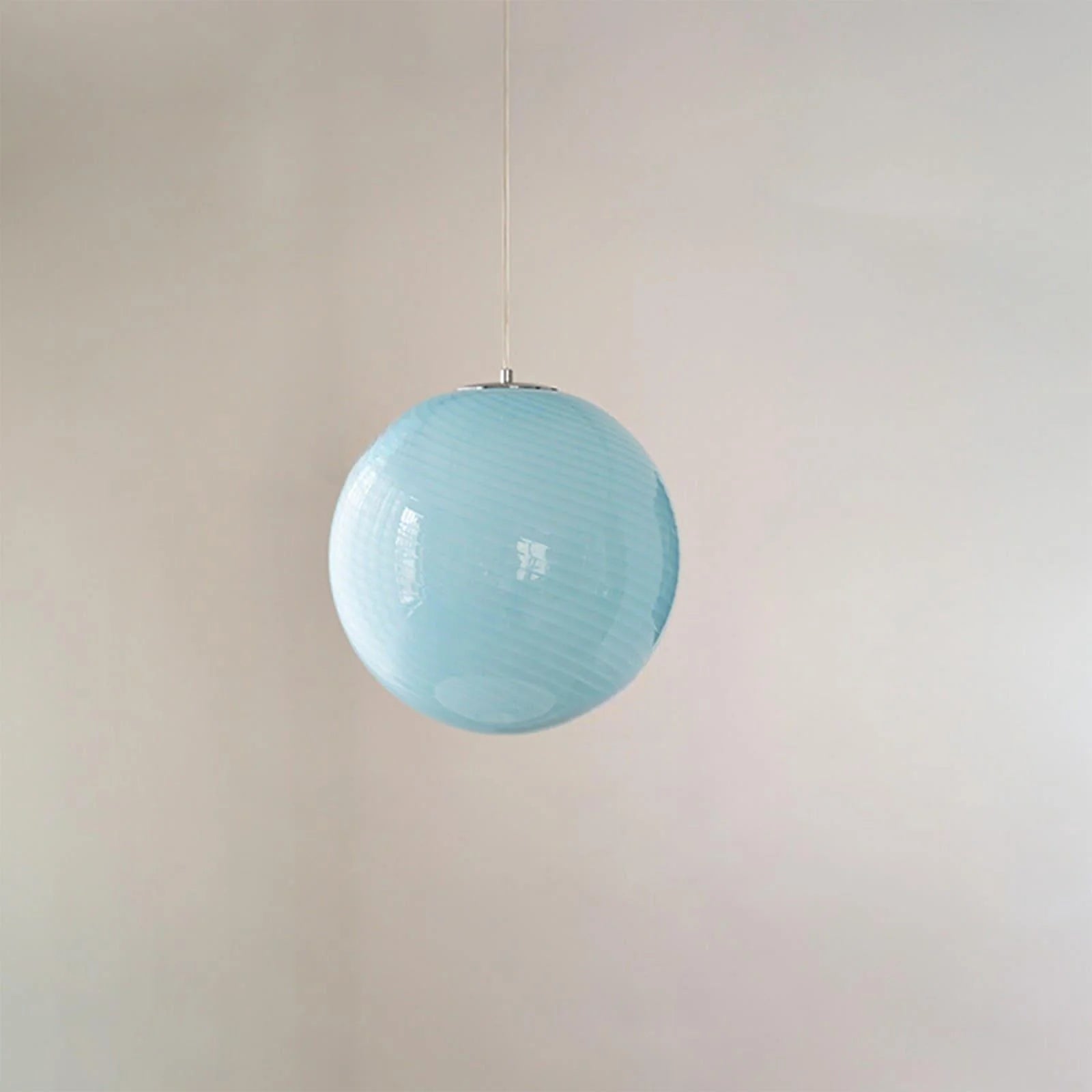 A modern spherical pendant light featuring a pale blue glass shade with a subtle white swirl pattern, suspended by a simple cord against a plain wall.