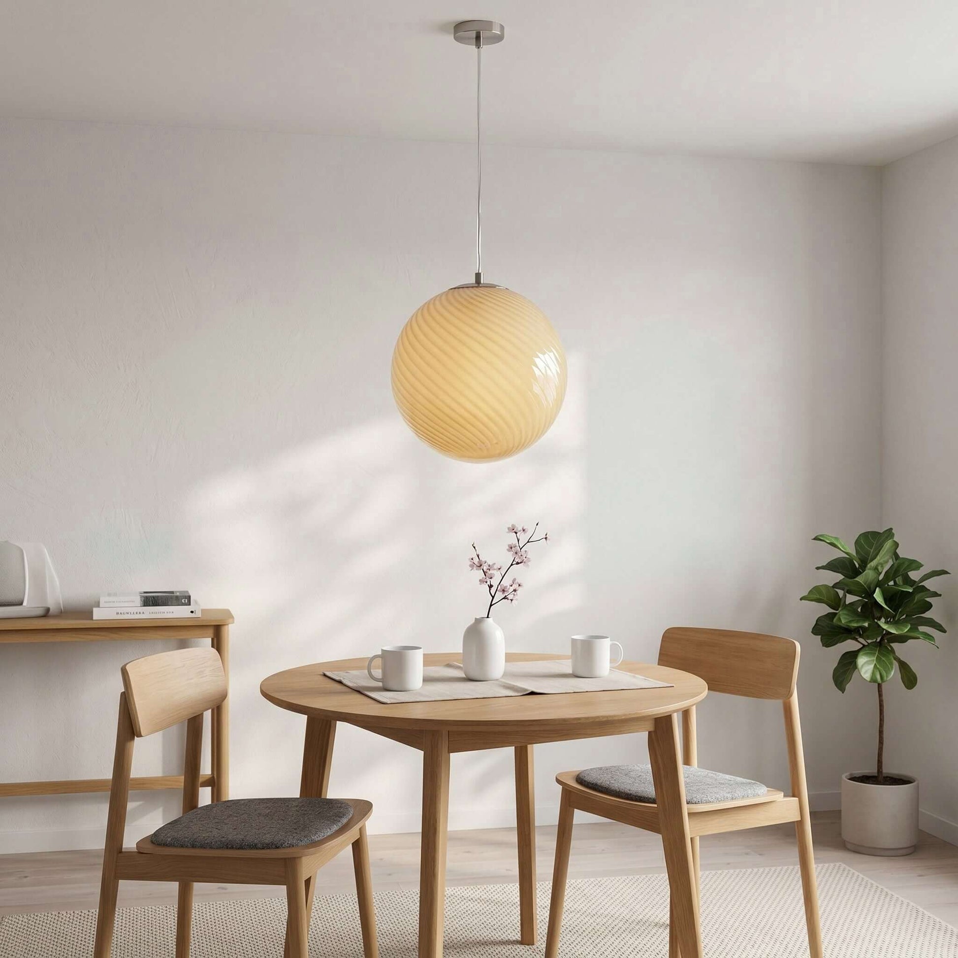 A modern spherical pendant light with a cream swirl glass shade hanging above a wooden dining table in a bright, minimalist dining room setting.