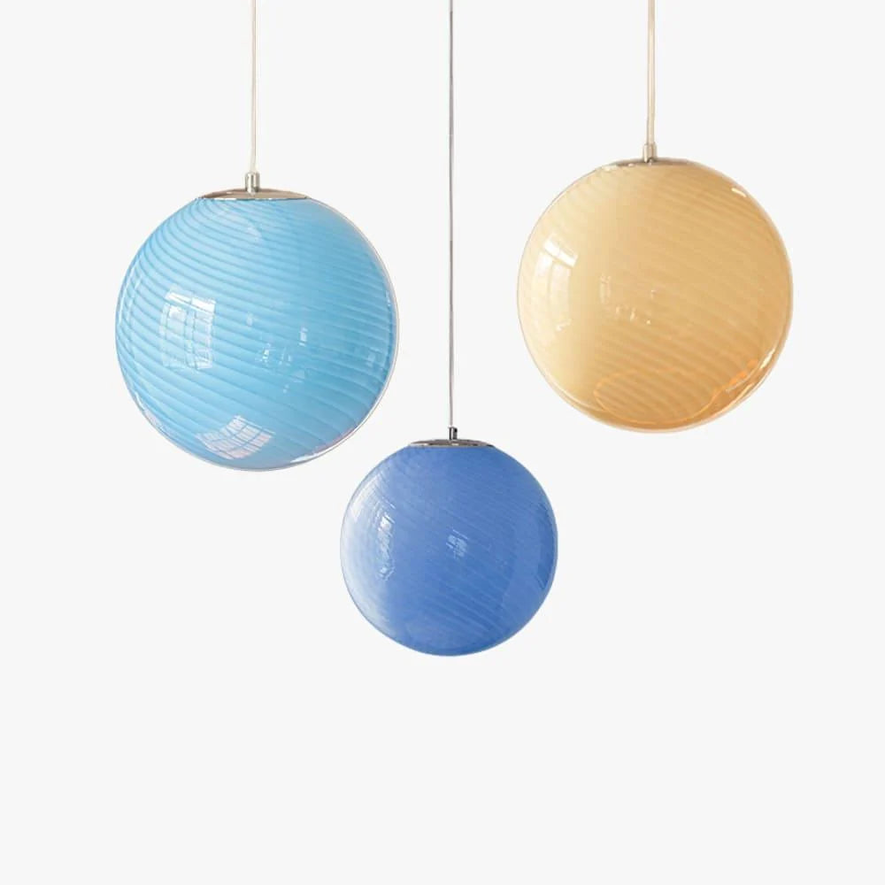 Three colourful swirl glass pendant lights in shades of light blue, medium blue, and amber, hanging at different heights against a white background.