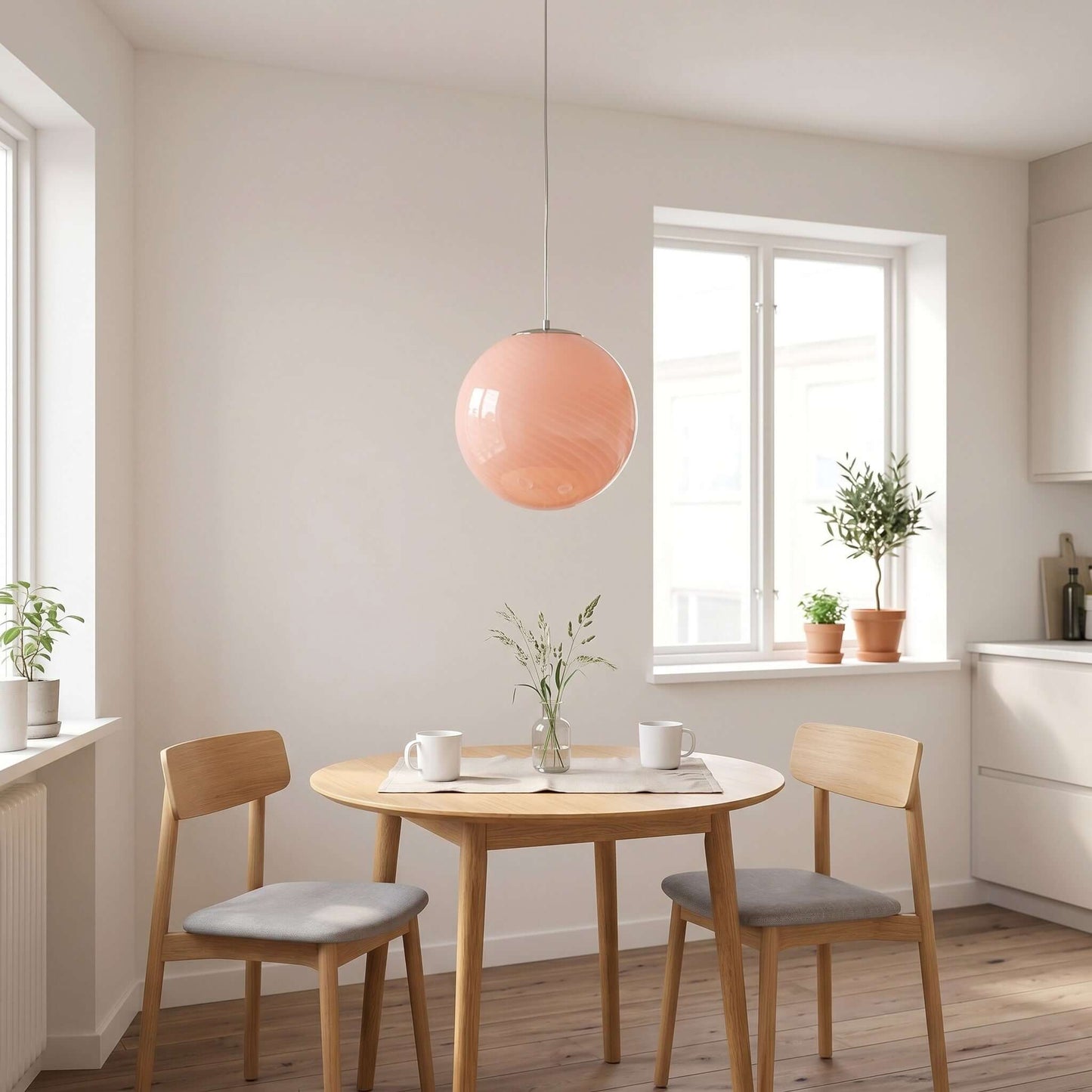 Pink swirl glass pendant light hanging above a round wooden dining table in a modern kitchen, creating a warm and inviting atmosphere.