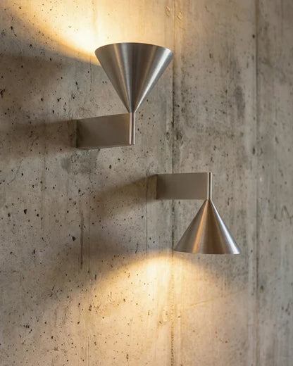 Brushed aluminum cone sconces on a textured wall