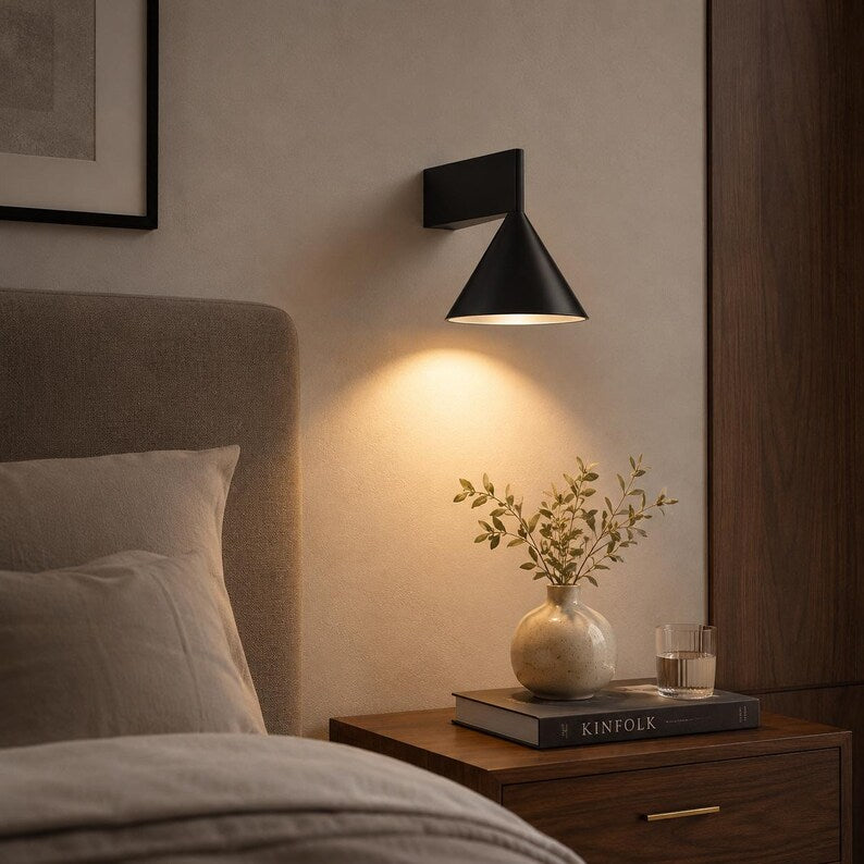Black cone wall lamp on a bedside wall
