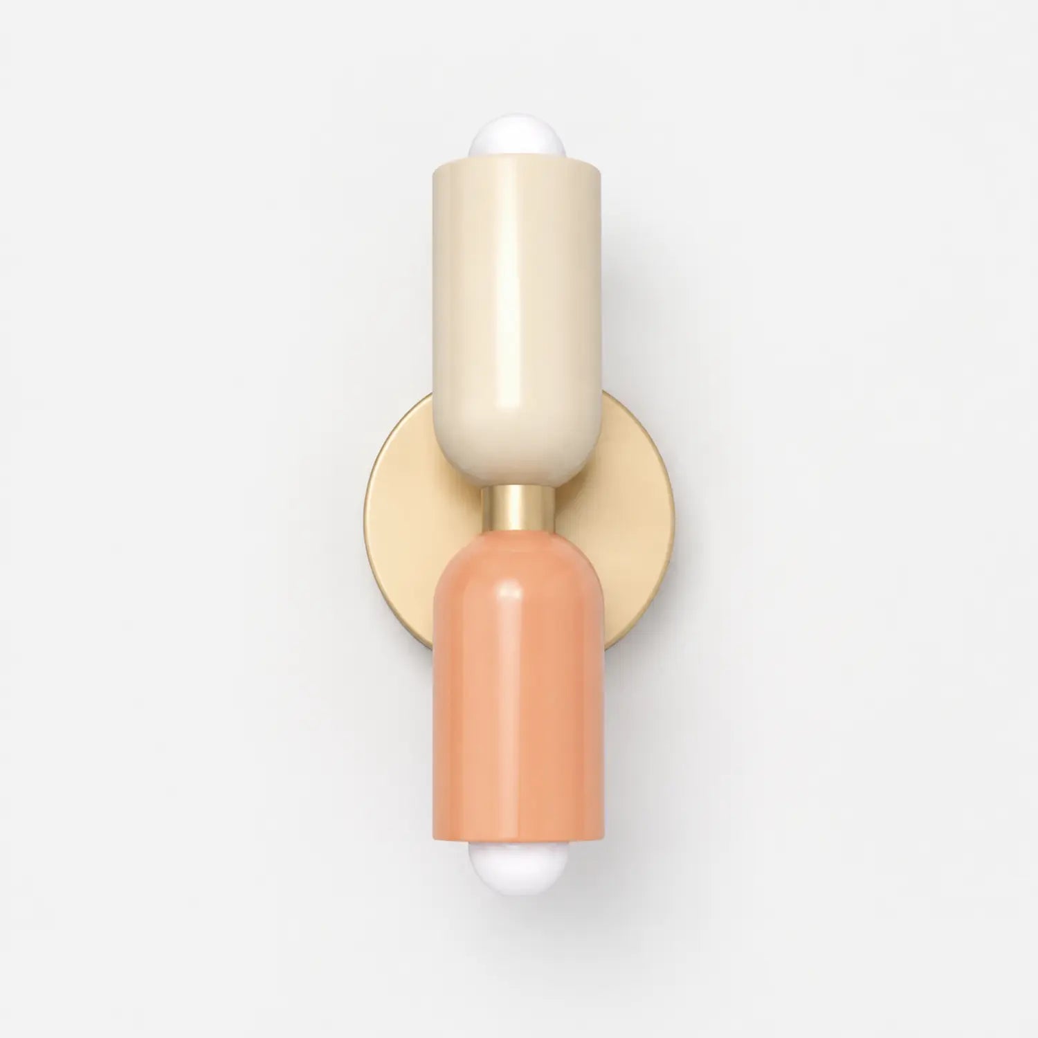 Contemporary dual-cylinder wall lamp featuring a cream and peach finish with a circular gold mounting plate, designed for up and down lighting.