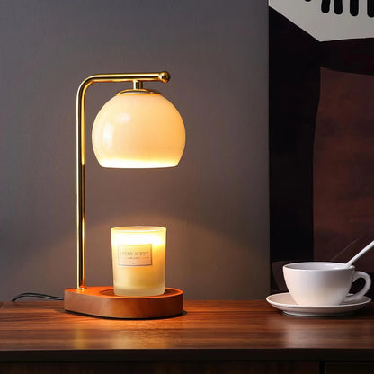 Glass globe candle warmer with gold metal arm and dark round base