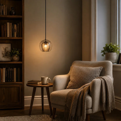 A 15cm amber ribbed glass globe pendant light hangs in a cosy living room, casting a warm glow above an armchair and a small wooden side table.