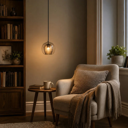 Contemporary 15cm amber ribbed glass globe pendant light hanging above a cosy reading nook with a wooden side table and armchair in a living room.