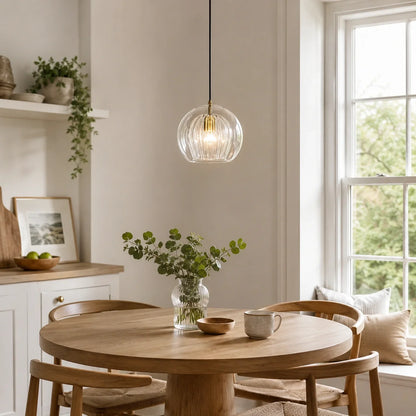 25cm contemporary clear ribbed glass globe pendant light hanging above a round wooden dining table in a bright, modern kitchen interior.