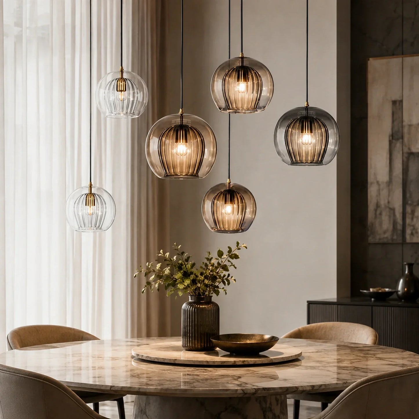 A cluster of contemporary ribbed glass globe pendant lights with warm glowing bulbs hanging above a marble dining table in a modern kitchen setting.