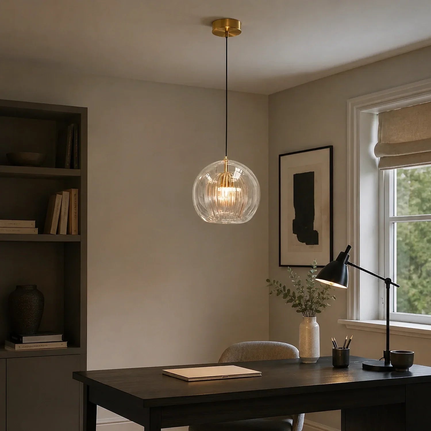 Contemporary ribbed glass globe pendant light with a brass finish, suspended above a dark wooden desk in a modern home office setting.