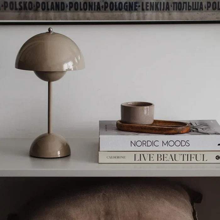 Grey cordless dome lamp beside books and a cup