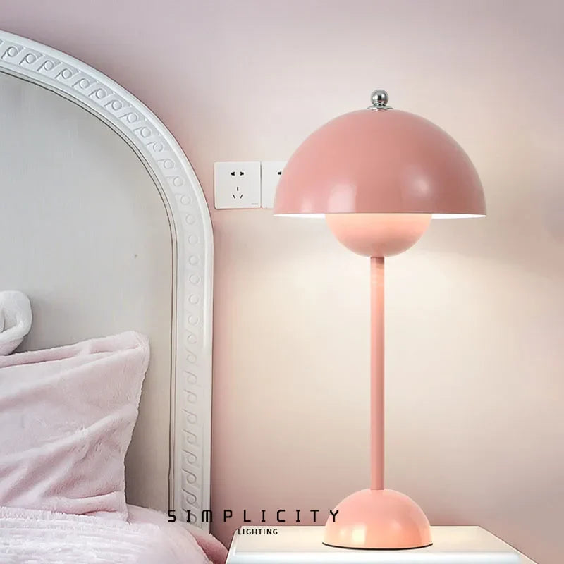Pink dome lamp beside a bed and mirror
