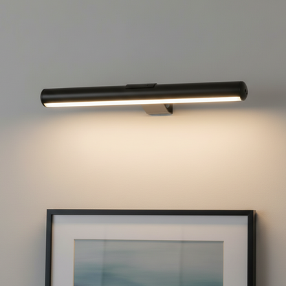 Black cordless picture light mounted above a frame