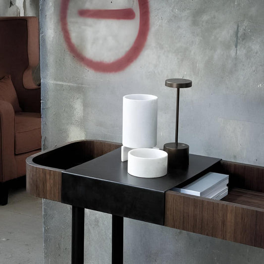 Black cordless table lamp on a side table beside white accessories